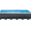 Intex metal-frame above-ground swimming pool with water, safety ladder, and sand filtration unit on white background.